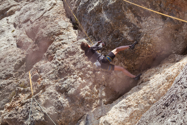 Een tiener op een rots is bezig met rotsklimmen, kindersporten in de natuur, buitenactiviteiten voor kinderen - Foto, afbeelding