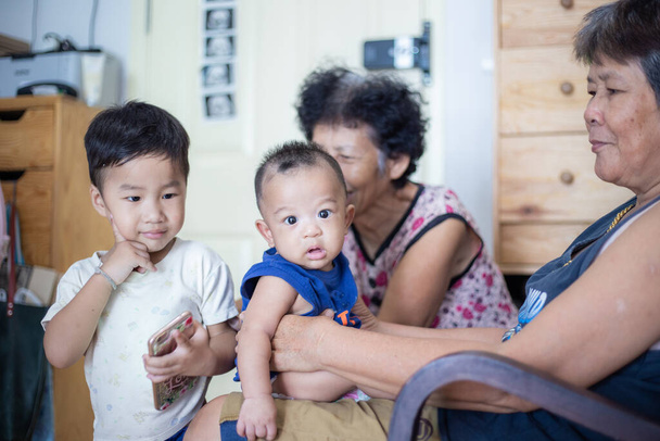 Glücklich lächelnde grondmather tragen mit ihrem kleinen Enkel im gemütlichen Zimmer genießen Familienzeit - Foto, Bild