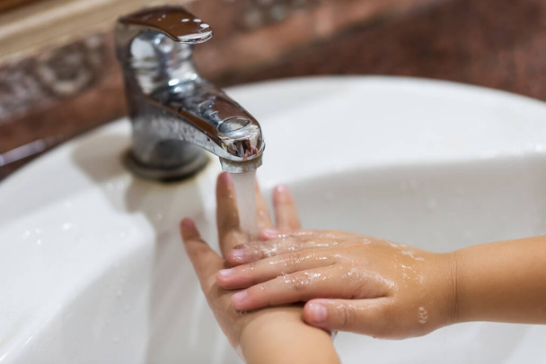 niño lavarse las manos enjuagando el jabón con agua de movimiento en el fregadero. covid-19 prevención por higiene de manos. Protección contra la pandemia de enfermedades mediante la limpieza de brazos. Detener el Coronavirus
. - Foto, Imagen