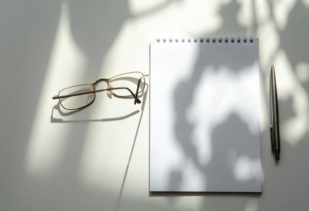 On a white background lies a notebook. Glasses on top, wrist watches below. On the side is a pen. The concept is business. Copy space - Photo, Image