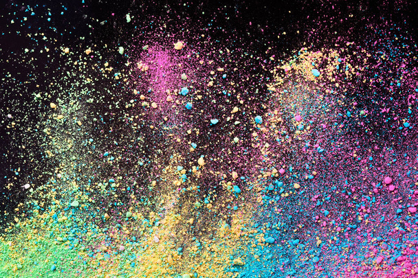 An explosion of colorful pigment powder on black background. Vibrant color dust particles textured background. - Fotoğraf, Görsel
