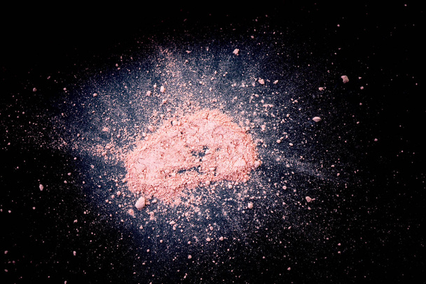 Halmaz természetes színezett pigment por. Rózsaszín por részecskék fröccsennek a fekete feketepiacon. - Fotó, kép