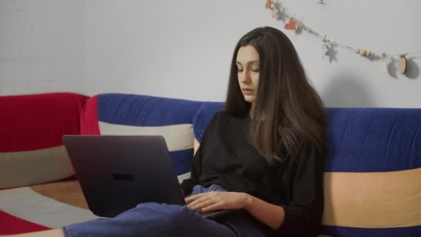 Junge Freiberuflerin arbeitet zu Hause am Laptop und sitzt auf dem bequemen Sofa. Freelancer Bloggerin arbeitet zu Hause mit Laptop. Blogger-Journalist arbeitet aus der Ferne. - Filmmaterial, Video