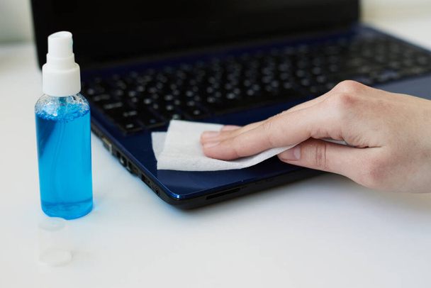 Desinfektionsgerät zum Schutz vor dem Ausbruch des Coronavirus covid-19. Reinigung der Hand mit antibakteriellen antiseptischen Desinfektionsmittel Spray Laptop - Foto, Bild