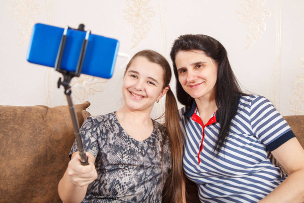 Máma a dcera si berou selfie s chytrým telefonem, zatímco sedí doma na gauči. koronavirová karanténa. - Fotografie, Obrázek