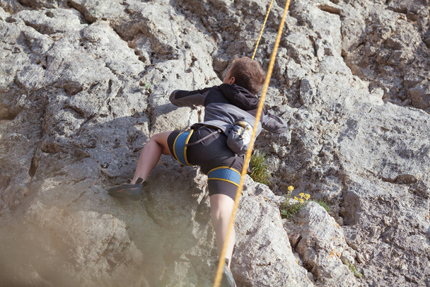 Nastolatek na skale zajmuje się wspinaczką skalną, sportem dziecięcym w przyrodzie, zajęciami plenerowymi dla dzieci - Zdjęcie, obraz