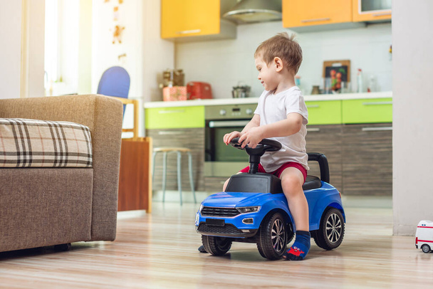 Feliz niño conducir en un coche de juguete en el piso. Actividad para un niño cuando se queda en casa. Organización del entretenimiento para el niño
. - Foto, Imagen