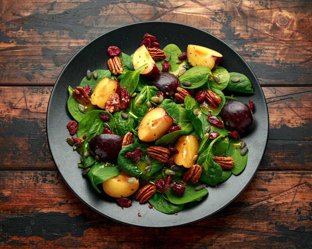 Veganský švestkový salát s brusinkami, dýňovými semínky, ořechy z ořechů, špenátem a hořčičným dresinkem - Fotografie, Obrázek