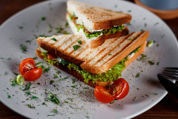 Toasted shredded chicken breast and salad sandwich served on a rustic wooden table wrapped in a brown paper wrapper tied with string with vignetting and copyspace - Photo, Image