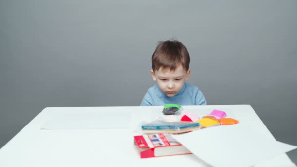 Video four year old boy sculpting in plasticine on gray background - Footage, Video