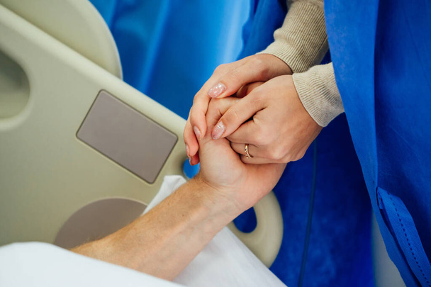 Holding patient hands in a hospital. Family help. Closeup. Support. - 写真・画像