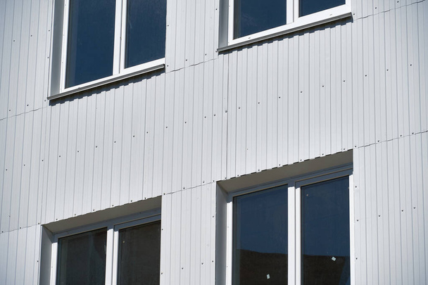 facciata di un nuovo edificio a più piani con raccordo in metallo bianco e verde, molte finestre
 - Foto, immagini