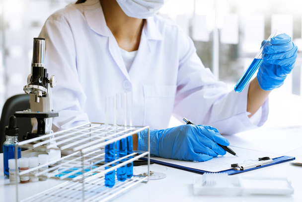 científicos que investigan en laboratorio en bata de laboratorio blanca, guantes que analizan, mirando la muestra de tubos de ensayo, concepto de biotecnología. - Foto, imagen