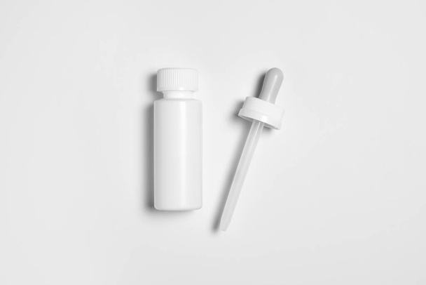 Plastic bottle with a pipette. Mock-up bottle with medical drug. Pharmacy blank packing. Medical dropper bottle.High resolution photo.Top view - 写真・画像