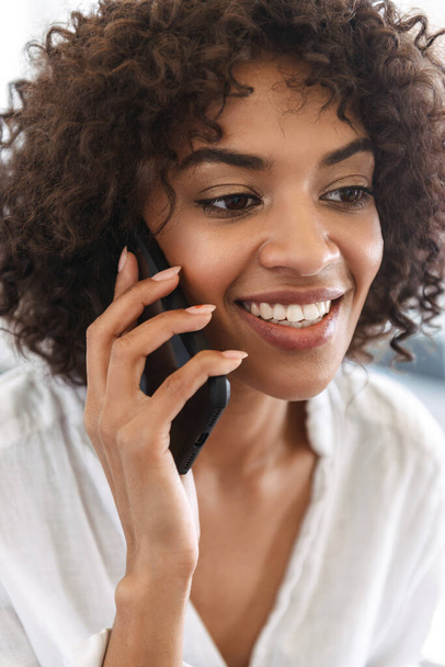 Gros plan d'une Africaine souriante parlant sur un téléphone portable isolé
 - Photo, image