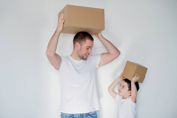 Caucasian dad and son with cardboard boxes on a white background at moving day. - Фото, зображення