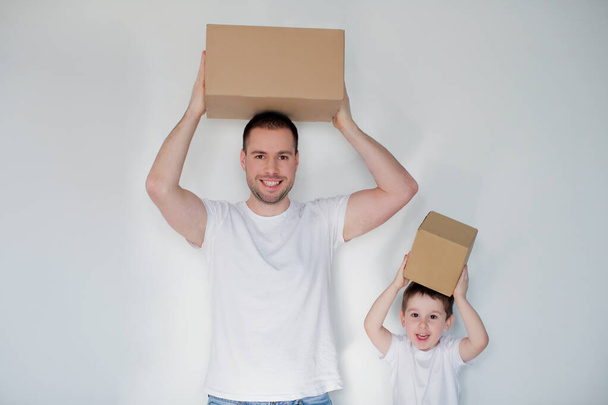 Père et fils caucasiens avec des boîtes en carton sur un fond blanc au jour du déménagement
. - Photo, image