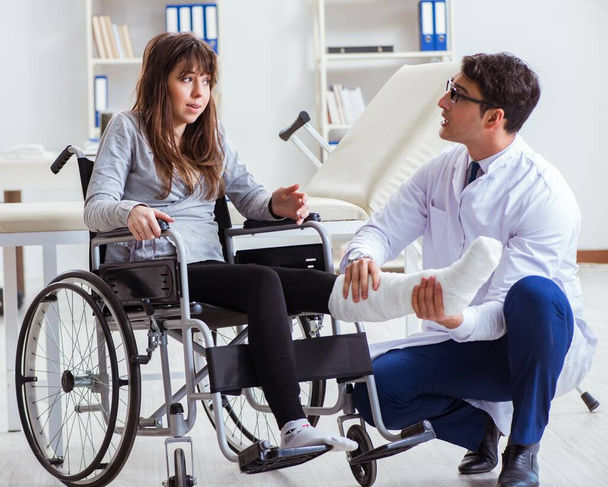 Male doctor examining female patient on wheelchair - Fotoğraf, Görsel