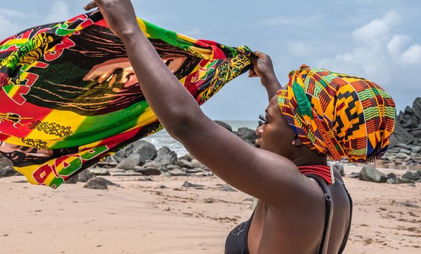 Ghana kobieta z nakryciem głowy w tradycyjnych kolorach z Afryki na pięknej plaży Axim, położony w Ghanie Zachodniej Afryki. Zdjęcie zrobione 2019 19 września - Zdjęcie, obraz