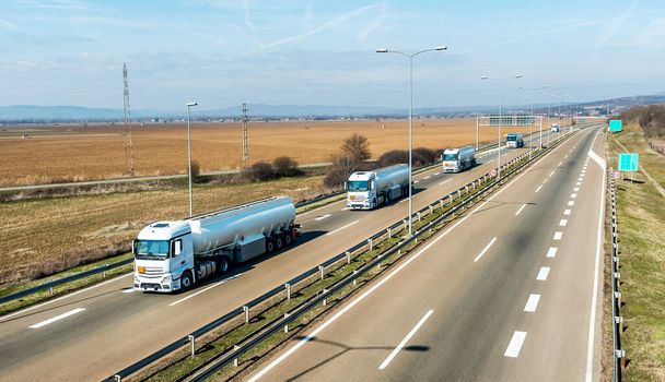 Konvooi of Caravan van tankwagens of reservoirs op een snelweg door het landelijke landschap. Bedrijfstransport en Trucking Industrie. - Foto, afbeelding