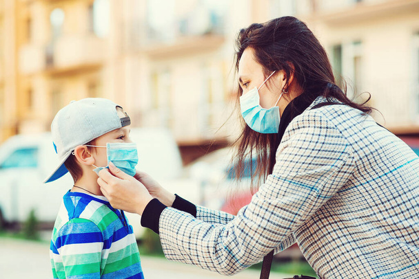 La madre pone a su hijo una máscara protectora al aire libre. Detengan la propagación del coronavirus. Cuarentena por Coronavirus. Brote de Coronavirus. Lugar público lleno de gente. Las personas previenen la infección por virus
. - Foto, imagen
