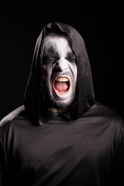 Portret ponurego żniwiarza krzyczącego na czarnym tle - Zdjęcie, obraz