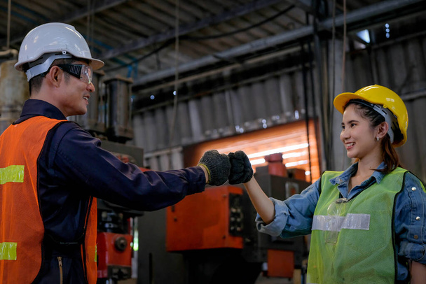 Técnico o trabajador hombre y mujer muestran acción de saludo para el éxito de su trabajo y se ven felices en el área de la fábrica
. - Foto, Imagen