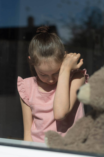A ten years little girl looking through the window. - Foto, Bild