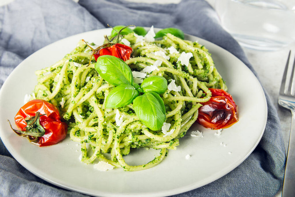 Pasta spaghetti with homemade pesto sauce, roasted tomatoes and fresh basil leaves, vegetarian food - Фото, изображение