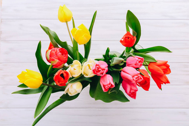 Vista superior de tulipanes de color en jarrones sobre fondo de madera blanco
 - Foto, imagen
