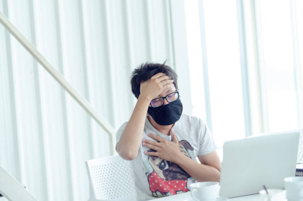 Азиатские мужчины, носящие очки Работает черная маска. Больной человек, сидящий за работой.. - Фото, изображение