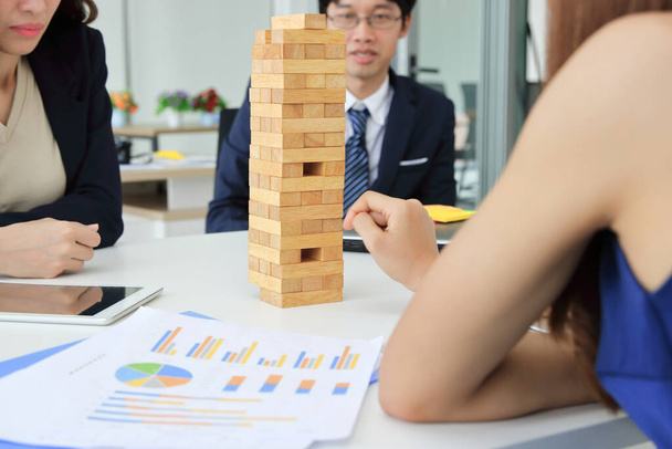 Задумчивая и внимательная группа бизнесменов, играющих в офисной деревянной башне. Концепция риска и стратегии бизнеса
. - Фото, изображение
