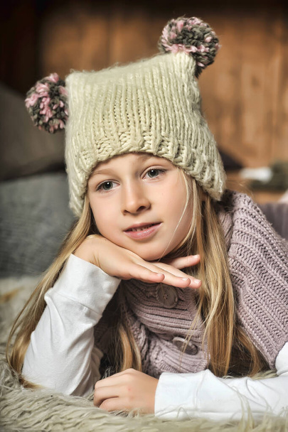 Blondes Mädchen in Strickkleidung und Hut mit Bommeln - Foto, Bild