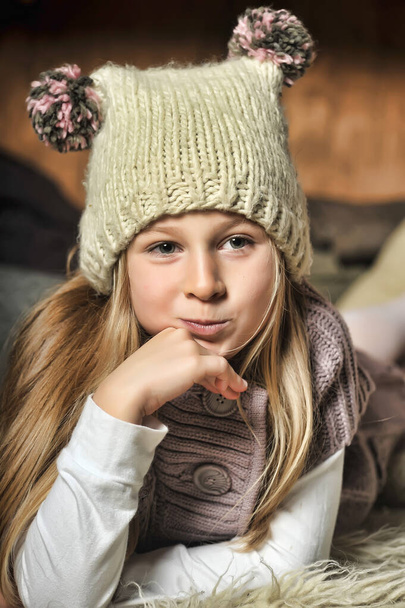 blonde girl in knitted clothes and a hat with pompons - Фото, изображение