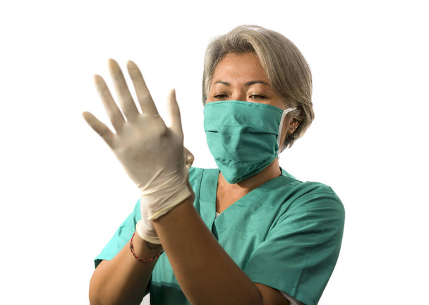 mature attractive and happy medicine doctor woman or hospital nurse in medical scrubs and face mask putting latex gloves confident fighting covid-19 virus pandemic - Photo, Image