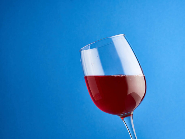 Kırmızı şarap büyük bir kadehte, mavi arkaplanda..    - Fotoğraf, Görsel