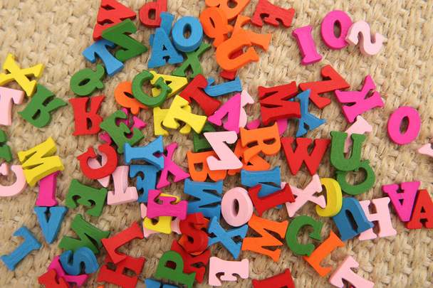 Többszínű fa betűk piros, zöld, kék, rózsaszín és sárga. A betűk egy gyermek játék & szétszórva a padlón. Szórakoztató módja a helyesírásnak..  - Fotó, kép