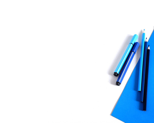 Colored pencils and markers on a blue white background. Suitable for advertising background. Mockup - Foto, imagen
