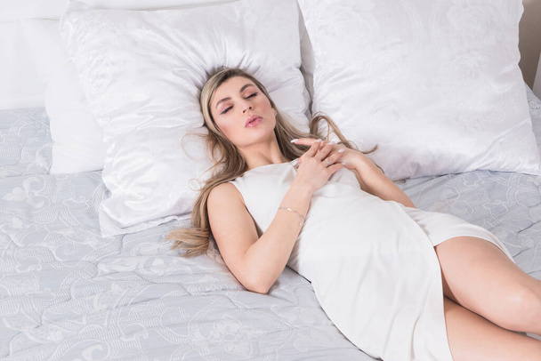 Сексуально привлекательная женщина в эротическом кружевном белье спит на кровати в спальне
.  - Фото, изображение