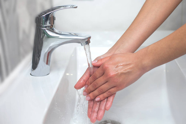 Lavagem das mãos. Uma mulher usa sabão e lava as mãos debaixo da torneira. conceito de higiene. Close-up
 - Foto, Imagem
