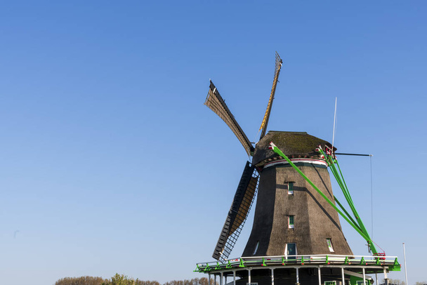Αεροφωτογραφία παλαιού ολλανδικού παραδοσιακού ανεμόμυλου στην ύπαιθρο της Ολλανδίας με ανάχωμα, κανάλια, γέφυρα και χωράφια. - Φωτογραφία, εικόνα