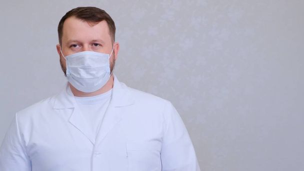 man in a protective mask and a white shirt looks at the camera, close-up. Hygiene concept. prevent the spread of germs and bacteria and avoid infection with the crown virus. copy space - Photo, Image