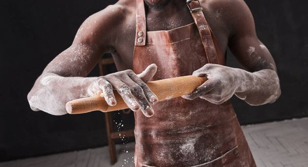 L'homme pâtissier à la peau foncée pétrit la pâte dans la cuisine. Chef pâtissier prépare la pâte à levure pour les pâtes à pizza
.  - Photo, image