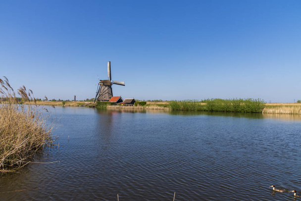 Veduta aerea di un vecchio mulino a vento tradizionale olandese sulla campagna rurale nei Paesi Bassi con una diga, canali, ponti e campi
. - Foto, immagini