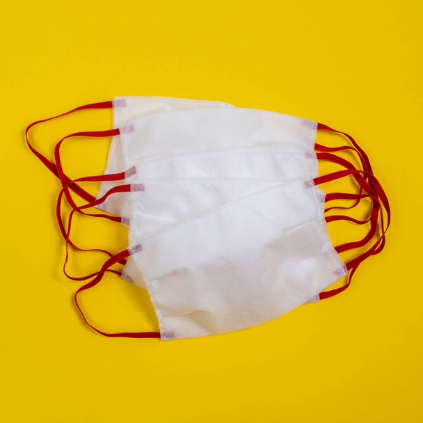 Медицинская защитная маска на желтом фоне. Одноразовая хирургическая маска для лица покрывает рот и нос резиновыми ушными ремешками. Процедура маска от бактерий. Концепция защиты, Здравоохранение
  - Фото, изображение