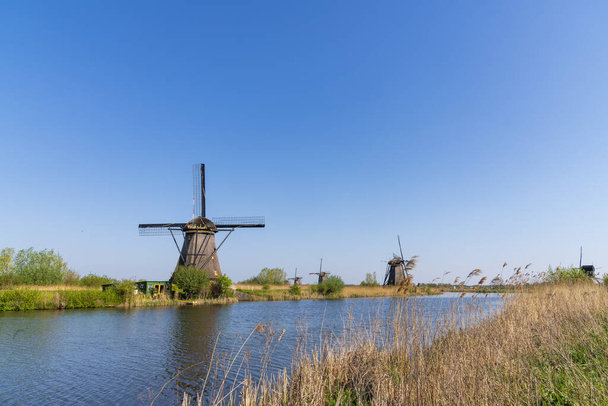 Veduta aerea di un vecchio mulino a vento tradizionale olandese sulla campagna rurale nei Paesi Bassi con una diga, canali, ponti e campi
. - Foto, immagini