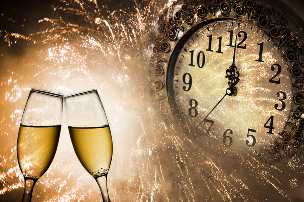 Бокалы для шампанского, часы и фейерверки в полночь
 - Фото, изображение