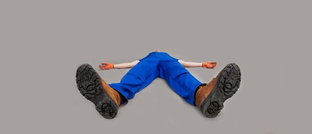 The worker lies on his back, legs forward. Exhausted or dead man was lying on the floor. The installer is swooning on the floor. - Foto, Bild