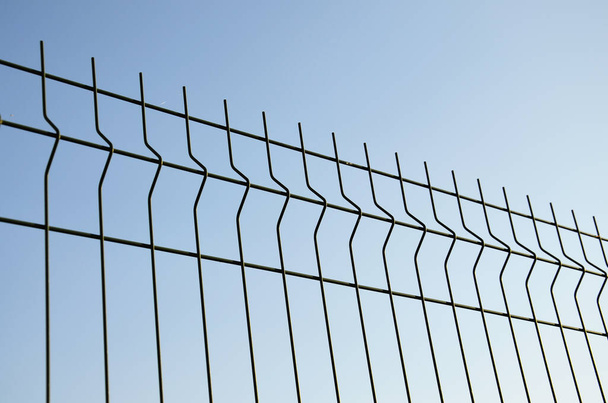 背景。青い空に対する金属製の柵。フェンスを閉じます。上を見ろ。デザインのため. - 写真・画像
