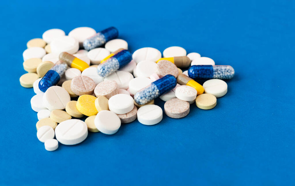 Heap of pills, tablets, capsules on blue background. Drug prescription for treatment medication health care concept wth copy space - Foto, imagen
